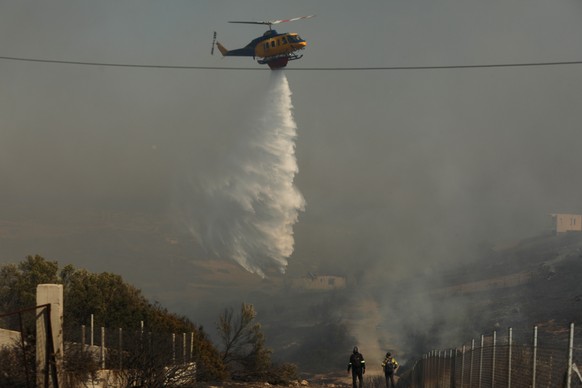 epa12199085 A firefighting helicopter douses a wildfire burning in the coastal region of Palaia Fokaia, some 40km southeast of Athens, Greece, 26 June 2025. Just after 12:30 p.m. on 26 June, a wildfir ...