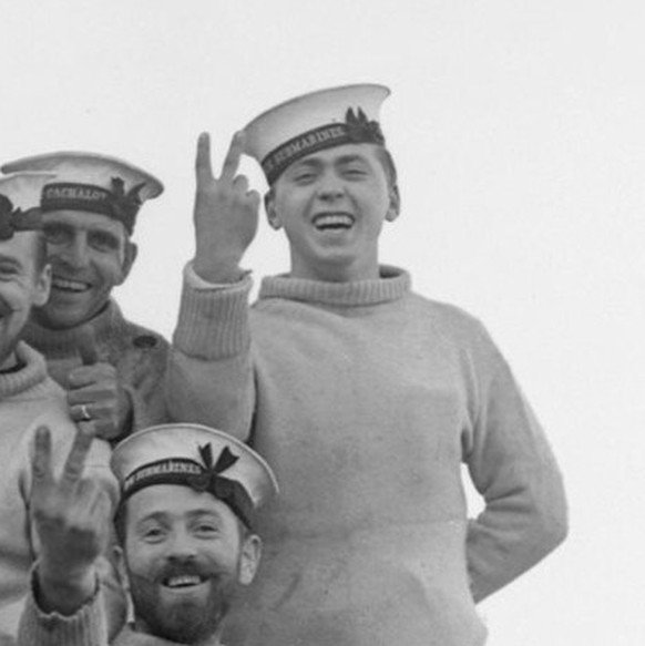 The personnel of the British submarine HMS Utmost showing off their Jolly Roger in February 1942. The markings on the flag indicate the boat&#039;s achievements: nine ships torpedoed (including one wa ...