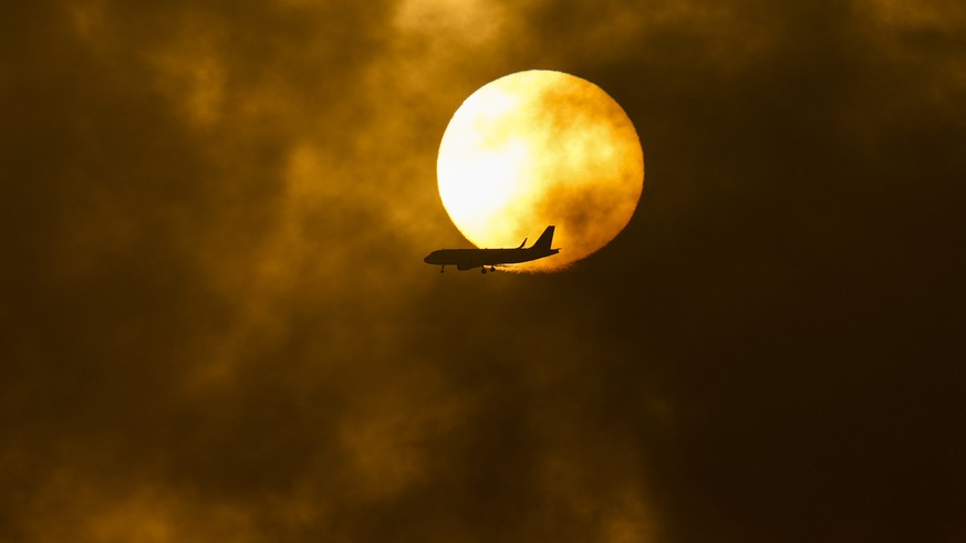 A passenger airplane flies between a smoldering fire at a Saudi Aramco oil depot after a Yemen Houthi rebel attack, ahead of a Formula One race as the sun rises in Jiddah, Saudi Arabia, Saturday, Marc ...