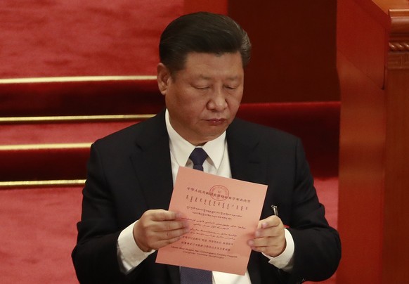 epa06595632 Chinese President Xi Jinping look at ballot papers before casting his vote during the third plenary session of the first session of the 13th National People&#039;s Congress at the Great Ha ...