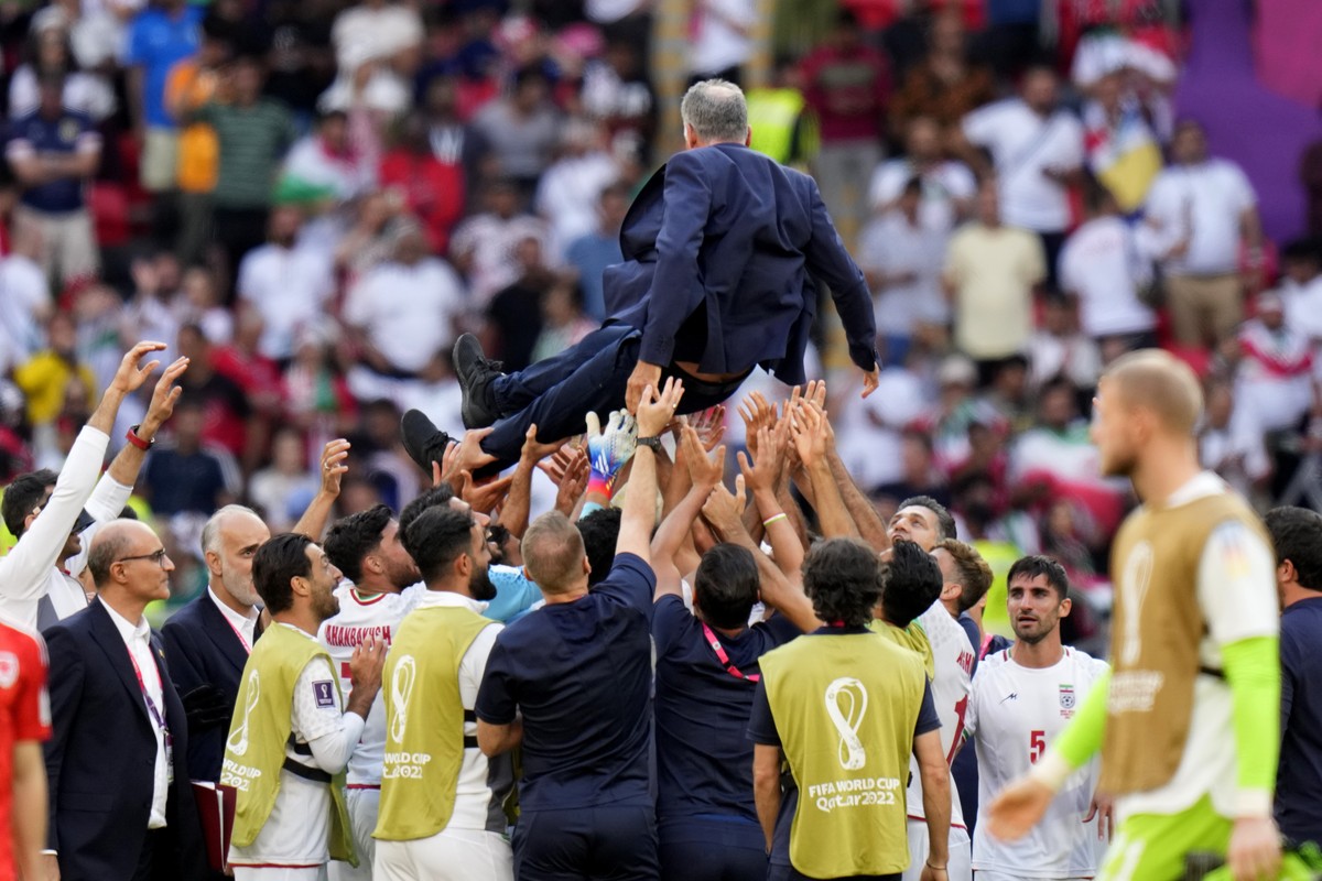 Players throw Iran's head coach Carlos Queiroz in air as they celebrate after their win in the World Cup group B soccer match between Wales and Iran, at the Ahmad Bin Ali Stadium in Al Rayyan, Qa ...