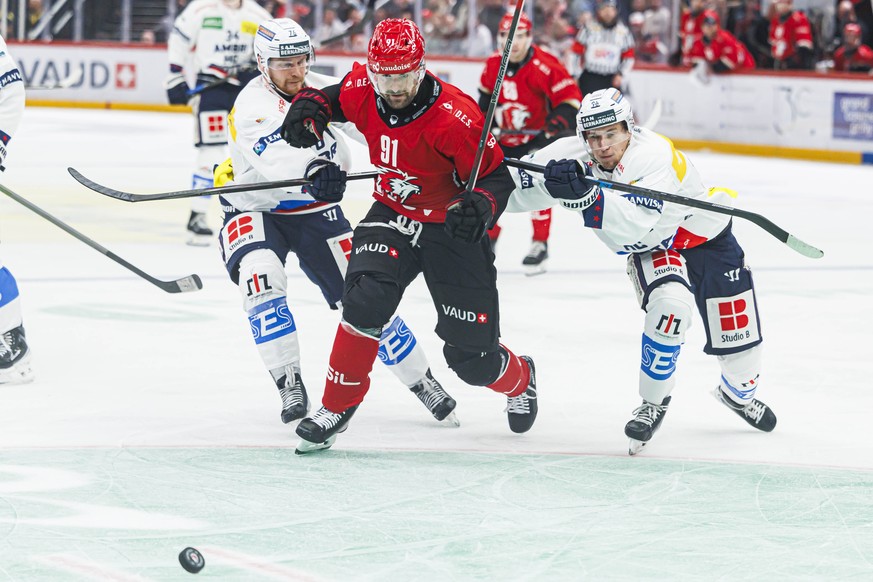 Fabian Heldner (LHC), centre, lutte pourle puck contre Nathan Schnarr (HCAP), gauche, et Aris Hafliger (HCAP), droite, lors de la rencontre de hockey sur glace de National League entre le Lausanne HC  ...