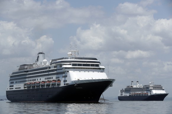 The Zaandam cruise ship, left, carrying some guests with flu-like symptoms, is anchored shortly after it arrived to the bay of Panama City, Friday, March 27, 2020, amid the worldwide spread of the new coronavirus. Health authorities are expected to board the ship to test passengers and decide whether it can cross the Panama Canal. (AP Photo/Arnulfo Franco)