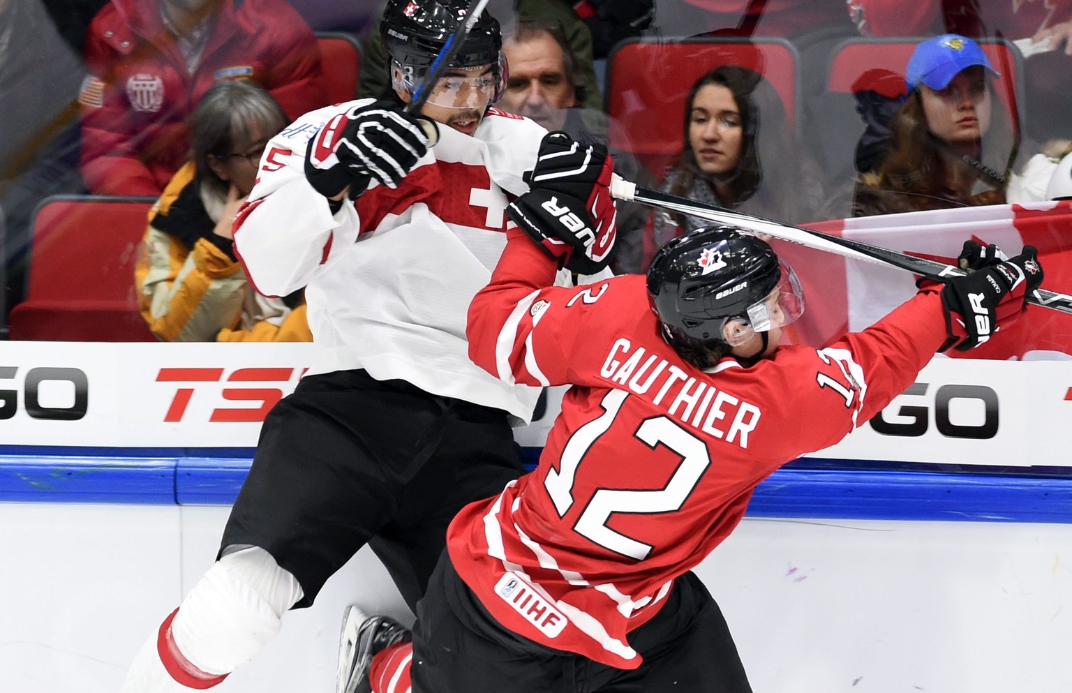 Canada&#039;s Julien Gauthier hits Switzerland&#039;s Jonas Siegenthaler into the boards during first-period preliminary hockey game action at the IIHF World Junior Ice Hockey Championship in Helsinki ...