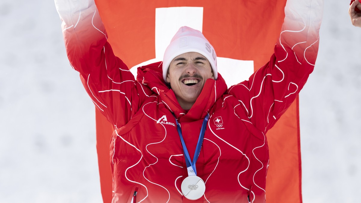 Switzerland's Noe Roth silver medallist celebrates with the Swiss flag during the medal ceremony after the men's Freestyle Skiing Freeski aerials final at the 2026 Olympic Winter Games in Li ...