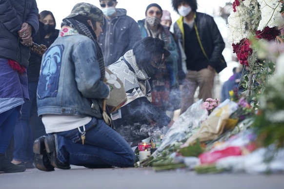 Mourners burn incense as they gather outside the door of a tattoo parlor along South Broadway Tuesday, Dec. 28, 2021, in Denver, one of the scenes of a shooting spree that left multiple people dead