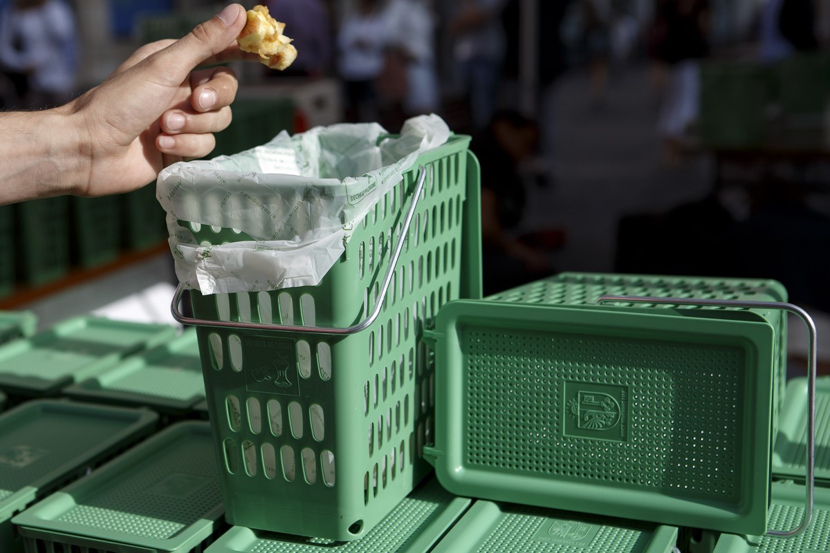 Une personne jette le reste d'une pomme dans une poubelle verte, lors du lancement de la distribution de 100'000 "P'tites poubelles vertes" pour la recuperation des dechets de ...