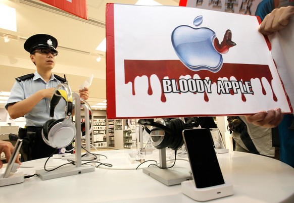 Nach dem Selbstmord Xu Lizhis: Ein Polizist neben einem Protestplakat, das sich gegen die unethischen Bedingungen von Apple und Foxconn richtet.