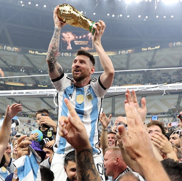 epa10373165 Lionel Messi of Argentina (C) lifts the trophy as he celebrates with teammates and fans winning the FIFA World Cup 2022 Final between Argentina and France at Lusail stadium, Lusail, Qatar, ...