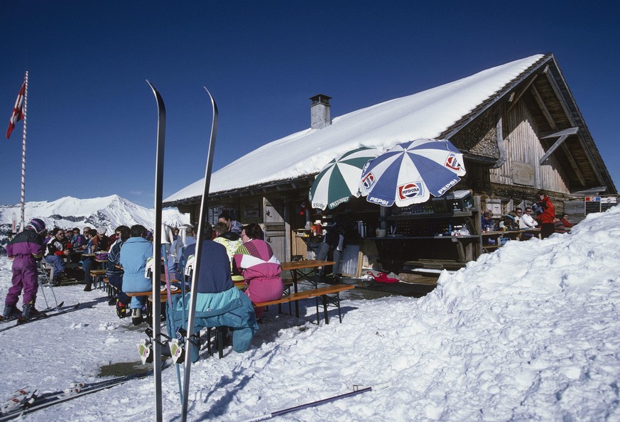 Südwestansicht der Berghütte/ Bergrestaurants Hilten mit Gästen im Winter, Skifahrer, Sonnenschirme auf der Terrasse, Gesamtansicht; Schlagworte Documenta Natura: Berghuette