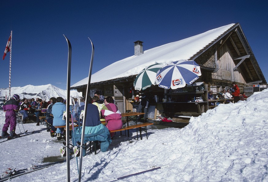 Südwestansicht der Berghütte/ Bergrestaurants Hilten mit Gästen im Winter, Skifahrer, Sonnenschirme auf der Terrasse, Gesamtansicht; Schlagworte Documenta Natura: Berghuette