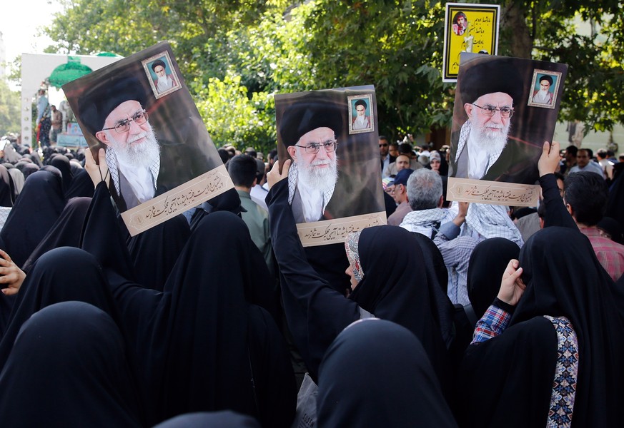 epa07676575 Iranians hold posters depicting Iranian supreme leader Ayatollah Ali Khamenei mourn during a ceremony in Tehran, Iran, 27 June 2019, marking the return of bodies of Iranian soldiers killed ...