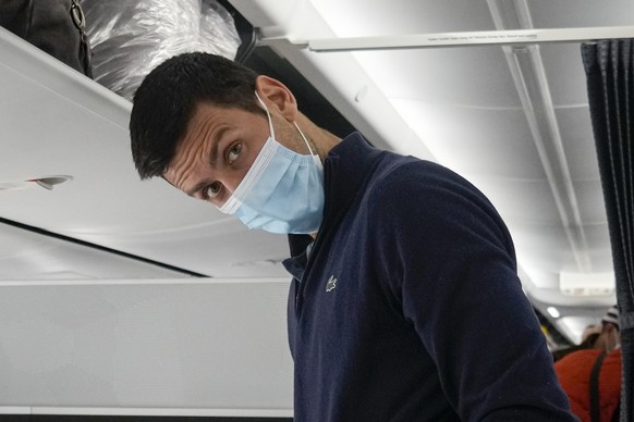 FILE - Recently deported from Australia for not being vaccinated against COVID-19, Novak Djokovic prepares to take his seat on a plane to Belgrade, in Dubai, United Arab Emirates, Monday, Jan. 17, 202 ...