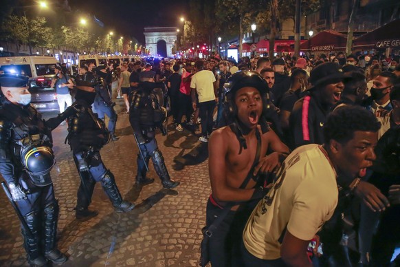 Police officers standby as supporters of the Paris Saint Germain soccer team celebrate on the Champs Elysee in Paris, Tuesday, Aug. 18, 2020 after PSG beat RB Leipzig 3-0 in a Champions League semifinal in Lisbon. (AP Photo/Michel Euler)