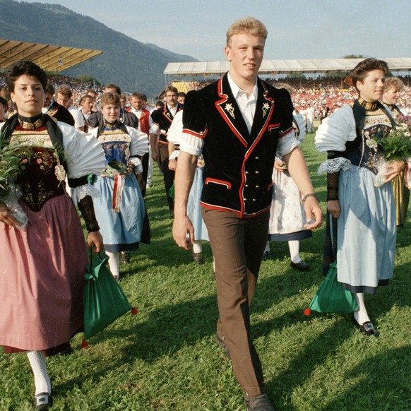 Der neue Schwingerkoenig Adrian Kaeser schreitet am 21. August 1989 in Stans beim Eidgenoessischen Schwing- und Aelplerfest, umgeben von Trachtenfrauen, zur Siegerehrung. (KEYSTONE/Martin Ruetschi)