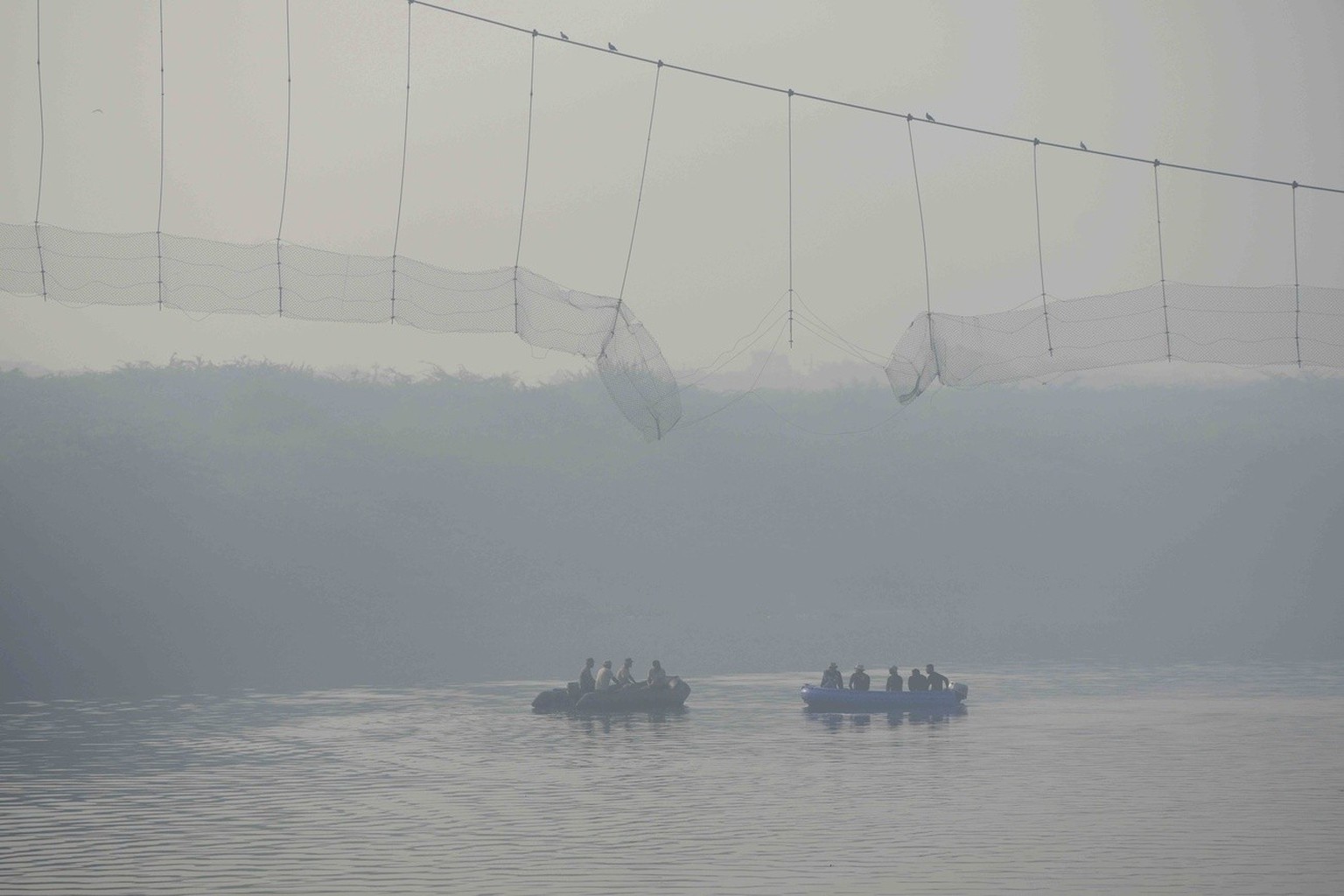 Rescuers on boats search in the Machchhu river next to a cable bridge that collapsed on Sunday in Morbi town of western state Gujarat, India, Wednesday, Nov. 2, 2022. A century-old cable suspension br ...
