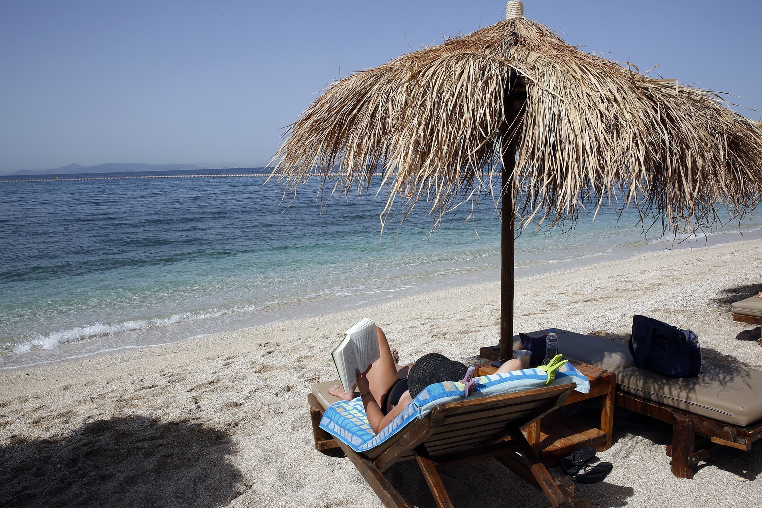 epa09186819 A woman enjoys a sunny day at the beach at a resort near Athens, Greece, 08 May 2021 (issued 09 May 2021). Equipped beaches charging entrance fees reopened on 08 May based on safety protoc ...