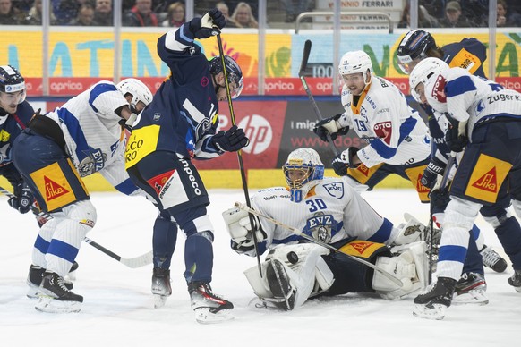Center, Ambri&#039;s player Dominic Zwerger fight for the puck with Zug&#039;s goalkeeper Leonardo Genoni, during the match of National League A (NLA) Swiss Championship 2023/24 between HC Ambri Piott ...