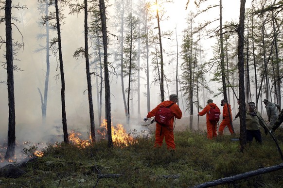 Firefighters and volunteers work at the scene of forest fire near Magan village in Yakutsk region, republic of Sakha also known as Yakutia, Russia Far East, on Tuesday, Aug. 10, 2021. Russian authorit ...