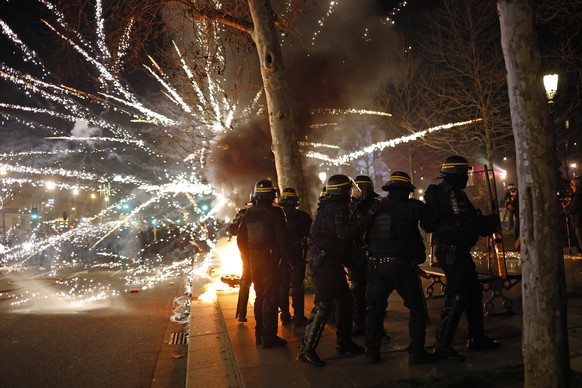 epa10535607 Fireworks explode as French riot police face protesters at Republique square during a demonstration against the government pension reform in Paris, France, 21 March 2023. Protests continue ...