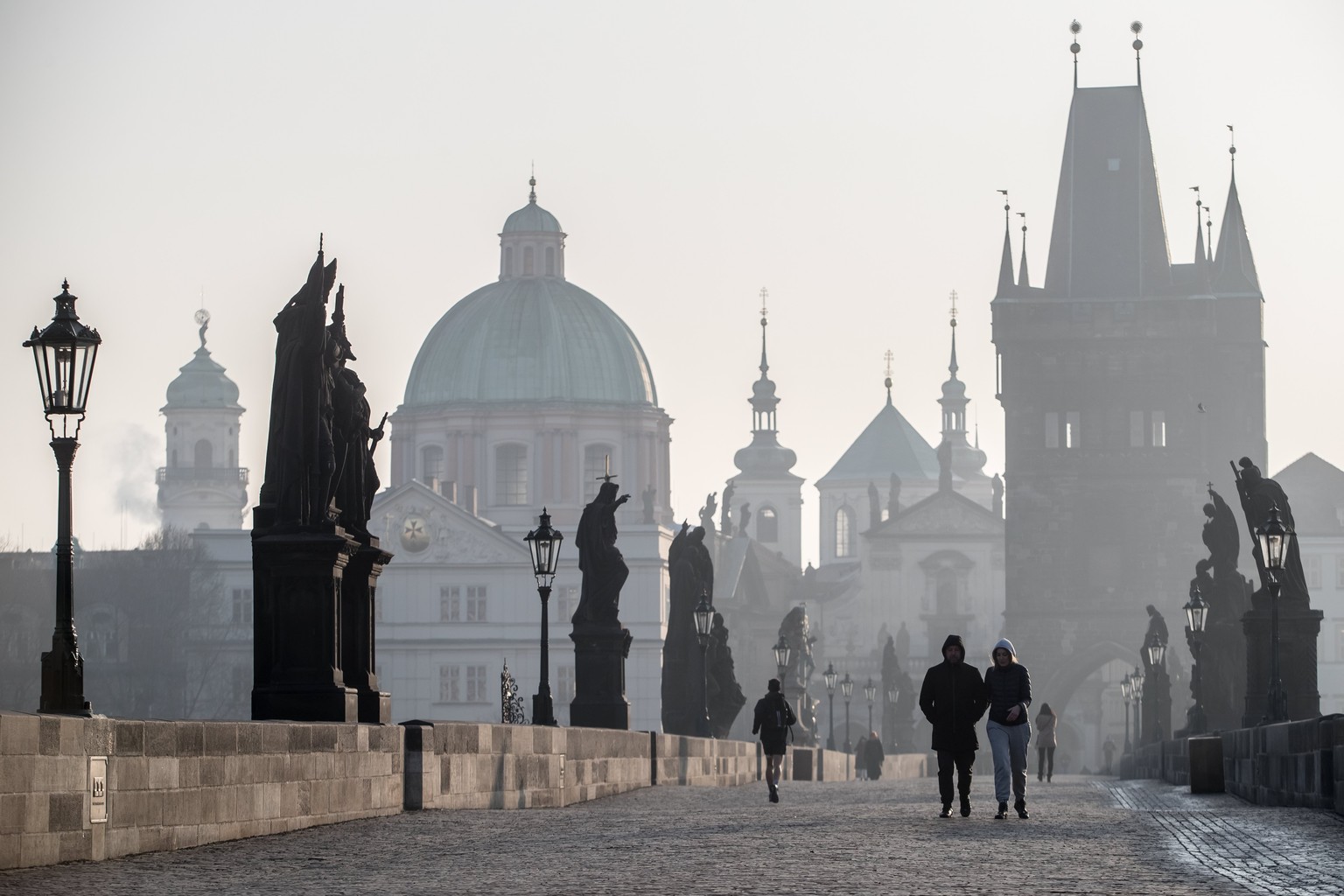 epa05796317 People walk across the Charles Bridge during smog in Prague, Czech Republic, 16 February 2017. Measuring stations in the city, and in the east parts of Czech Republic, noted an exceeded le ...