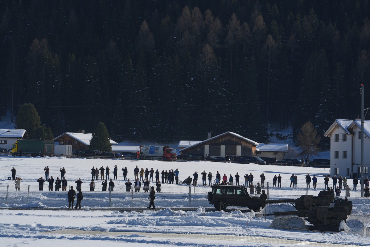 People stand on the ground and look up at Marine One, carrying President Donald Trump, as he arrives for the Annual Meeting of the World Economic Forum in Davos, Switzerland, Wednesday, Jan. 21, 2026. ...