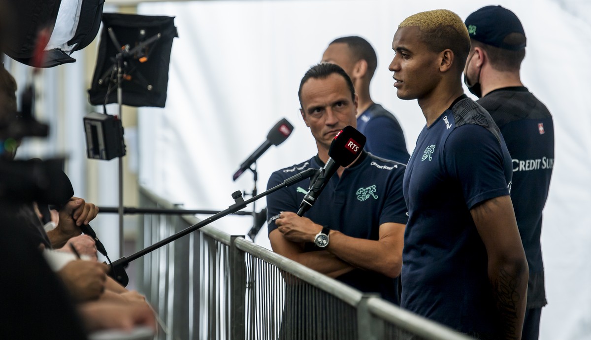 Switzerland's defender Manuel Akanji, speaks to journalists next to Adrian Arnold, left, head for the communication of the federation SFV during the Euro 2020 soccer tournament at the Tre Fontane ...
