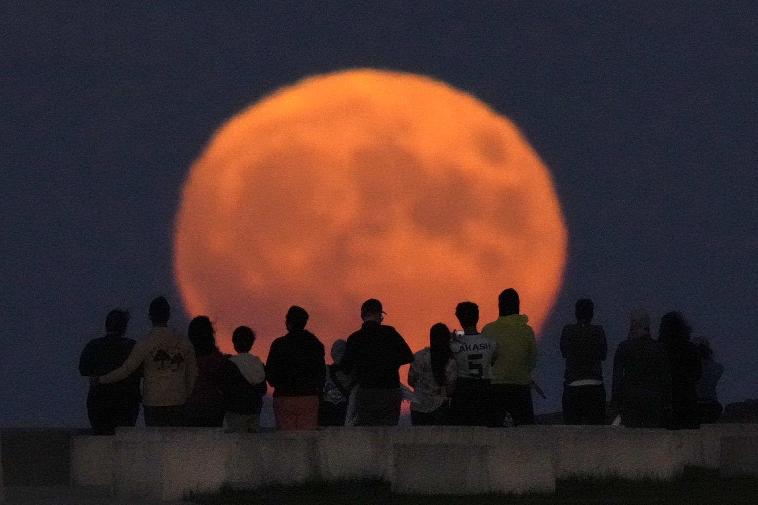 A rare blue supermoon rises over Lake Michigan as spectators watch from Chicago's 31st Street beach Wednesday, Aug. 30, 2023. (AP Photo/Charles Rex Arbogast)