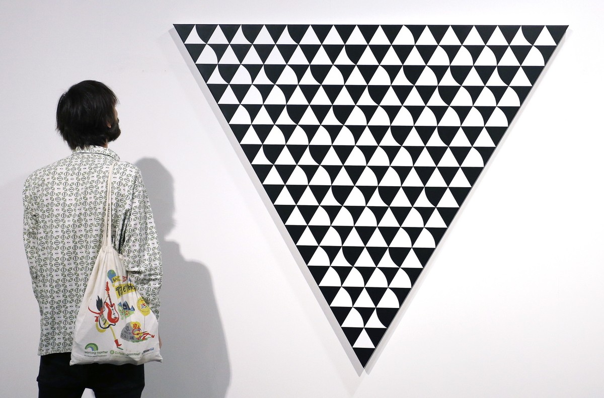 epa07215743 An Art Basel patron looks at 'Light Shade 7' by Bridget Riley during Art Basel in Miami, Florida, USA, 07 December 2018. Art Basel represents over 250 art galleries onsite at the ...
