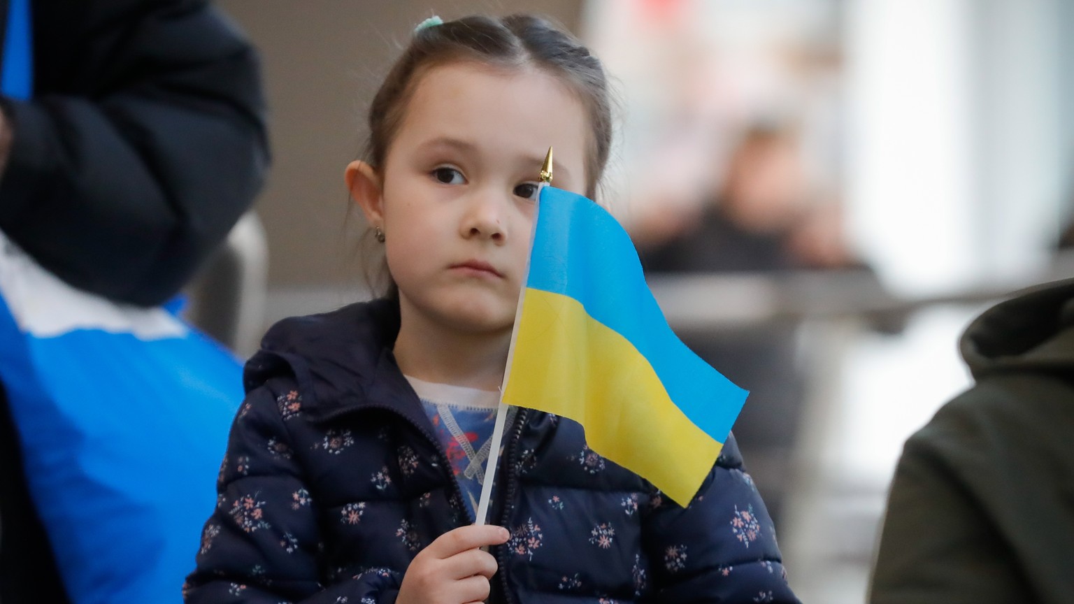 epa09842599 A young girl from a group of refugees who fled Ukraine following the Russian invasion waves a small Ukrainian flag as she along with others waits for further procedures after arrival by tr ...