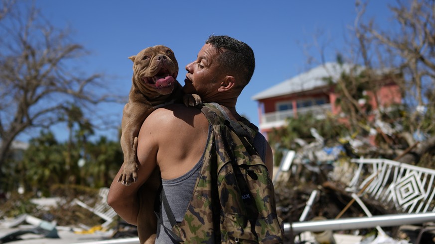 Eduardo Tocuya carries a dog he recovered in hopes of reuniting it with its owners, two days after the passage of Hurricane Ian, in Fort Myers Beach, Fla., Friday, Sept. 30, 2022. (AP Photo/Rebecca Bl ...
