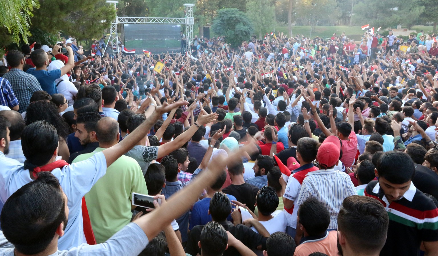 epa06186378 Syrian people watch the FIFA World Cup 2018 qualifying soccer match between Iran and Syria on a huge screen in a park in Damascus, Syria, 05 September 2017. The match between Iran and Syri ...