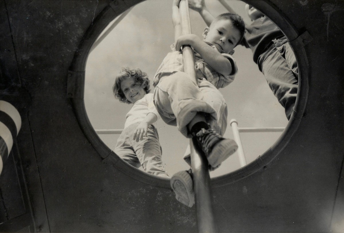 View, from below, as a young boy slides down fireman's pole at a playground, Florida, 1958. A girl watches from above. (Photo by The Harrington Family Collection/Getty Images)