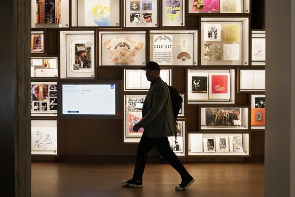 A man walks past a portion of the archive wall at the Bob Dylan Center, Thursday, May 5, 2022, in Tulsa, Okla. The center offers an immersive film experience, performance space, a studio where visitor ...