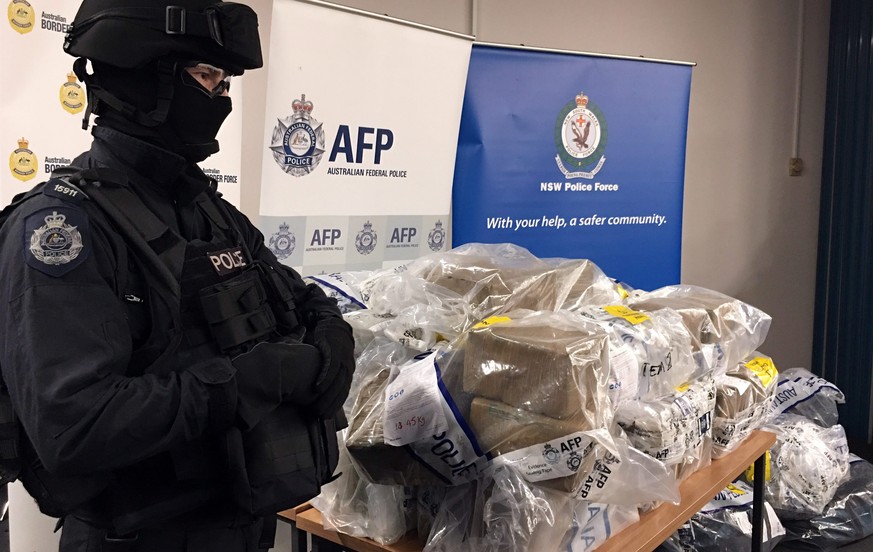 epa05690628 An Australian Federal Police Officer stands next to a pile of cocaine seized by police, at an undisclosed location in Australia, 29 December 2016. Approximately 500 kilograms of cocaine we ...