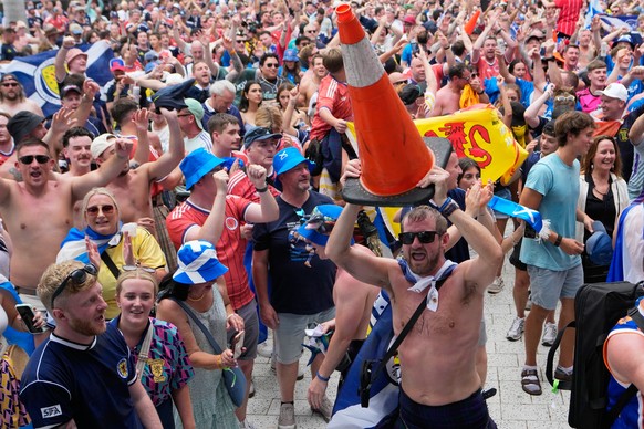 A Scotland soccer fan dances with a traffic cone as part of the Tartan Army march outside of loanDepot park before a baseball game between the Miami Marlins and the Texas Rangers, Monday, June 22, 202 ...