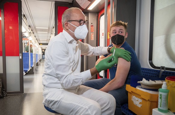 Christian Gravert, left, chief medical officer of the Deutsche Bahn, vaccinates a man with the Johnson &amp; Johnson vaccine in a special train of the public transport S-Bahn, in which vaccination aga ...