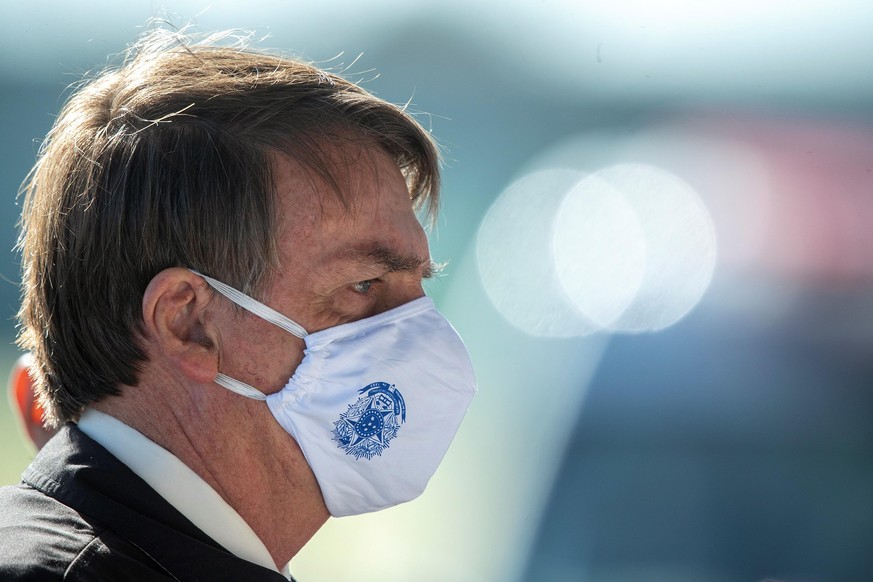 epa08438005 The President of Brazil, Jair Bolsonaro, wears a face mask while leaving the Palacio da Alvorada presidential residence, in Brasilia, Brazil, 22 May 2020. Magistrate Celso de Mello, dean o ...