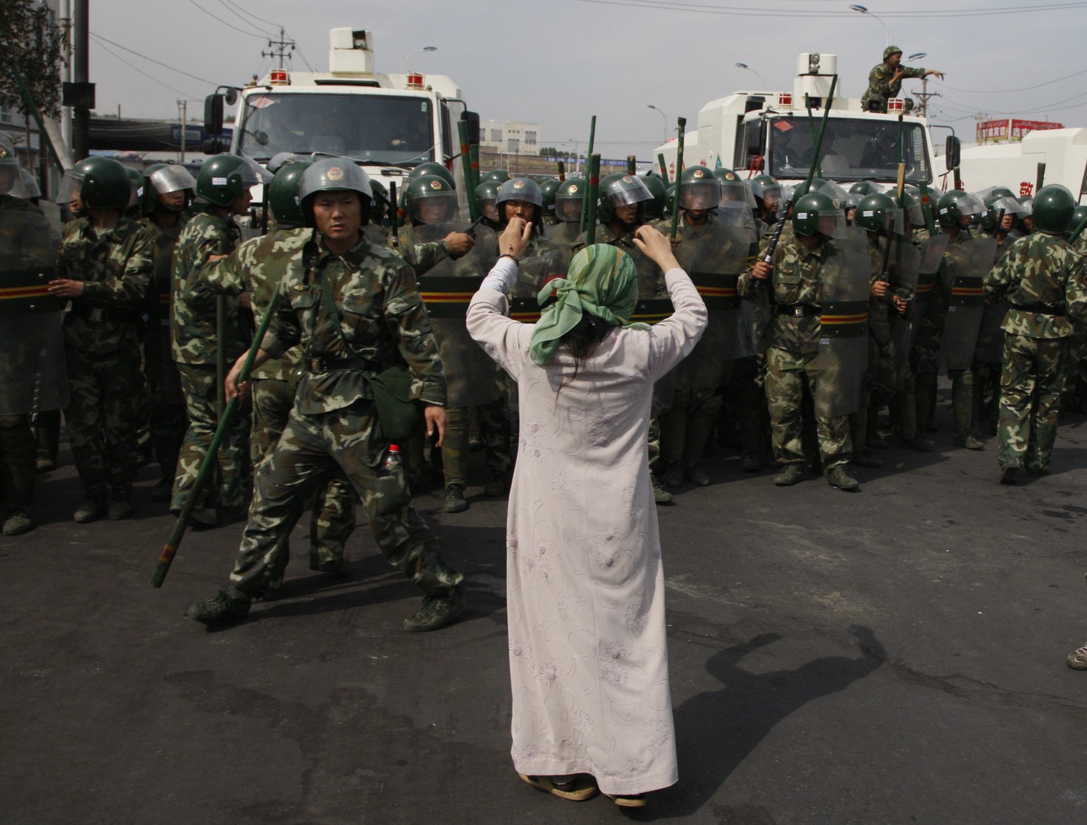 In this photo taken Tuesday, July 7, 2009, a Uighur woman protests before a group of paramilitary police when journalists visited the area in the aftermath of riots in Urumqi in western China's Xinjiang region. Analysts say the Urumqi riots in 2009 set in motion the harsh security measures now in place across Xinjiang, where about 1 million Uighurs, Kazakhs and other Muslims are estimated to be held in heavily-guarded internment camps _ also called 