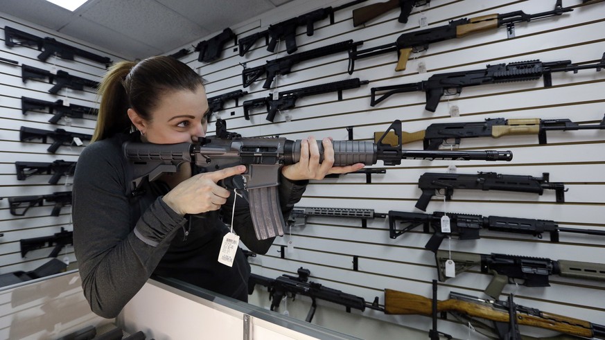 Gun shop owner Tiffany Teasdale-Causer points a Ruger AR-15 semi-automatic rifle, the same model, though in gray rather than black, used by the shooter in a Texas church massacre two days earlier, as  ...