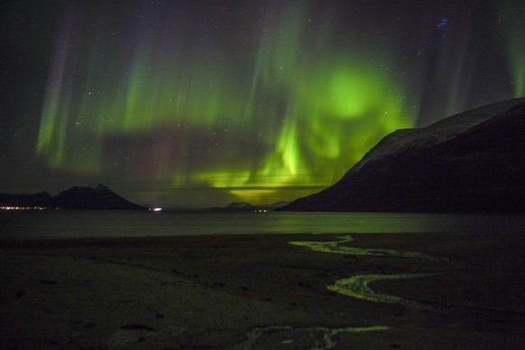 epa04457367 A Northern light (Aurora borelias) can bee seen outside the city Tromso in Northern Norway, late 21 October 2014. The white dot right left of the picture centre, is one of the famous ships ...