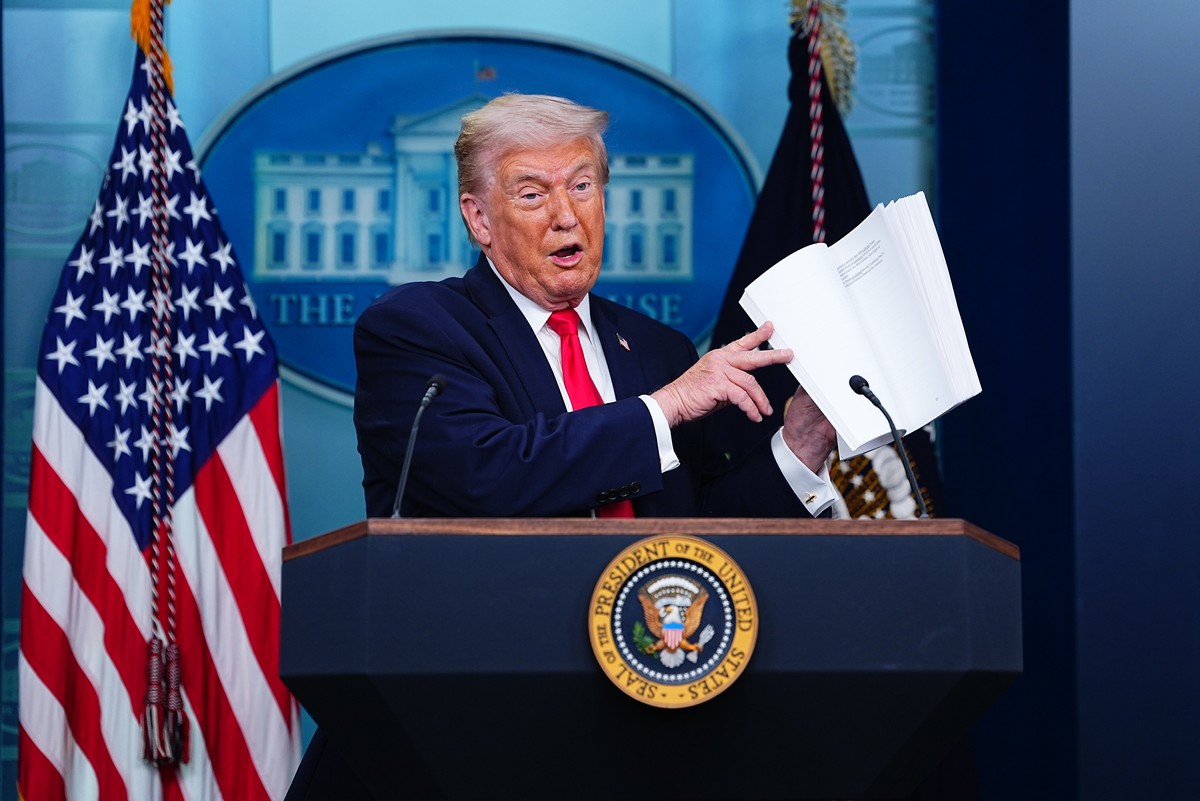epa12665415 US President Donald J Trump leafs through a book of his administration?s accomplishments as he joins the White House briefing in the James S Brady Press Briefing Room of the White House in ...