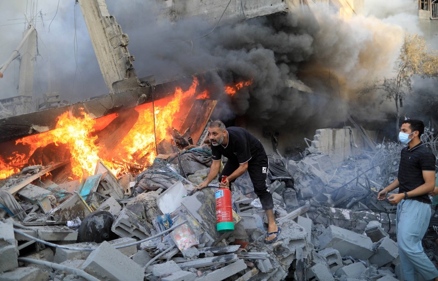 231014 -- GAZA, Oct. 14, 2023 -- People extinguish fire among rubble of a building after an Israeli air strike in the southern Gaza Strip city of Khan Younis, Oct. 14, 2023. The ongoing conflict betwe ...
