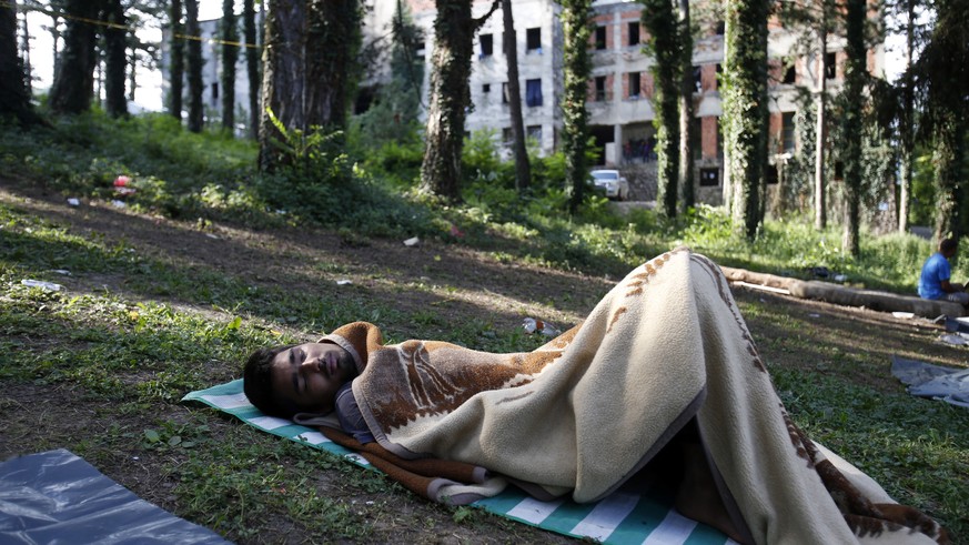 In this photo taken on Tuesday, Aug. 14, 2018, a migrant man sleeps on the ground a makeshift migrant camp in Bihac, 450 kms northwest of Sarajevo, Bosnia. Impoverished Bosnia must race against time t ...