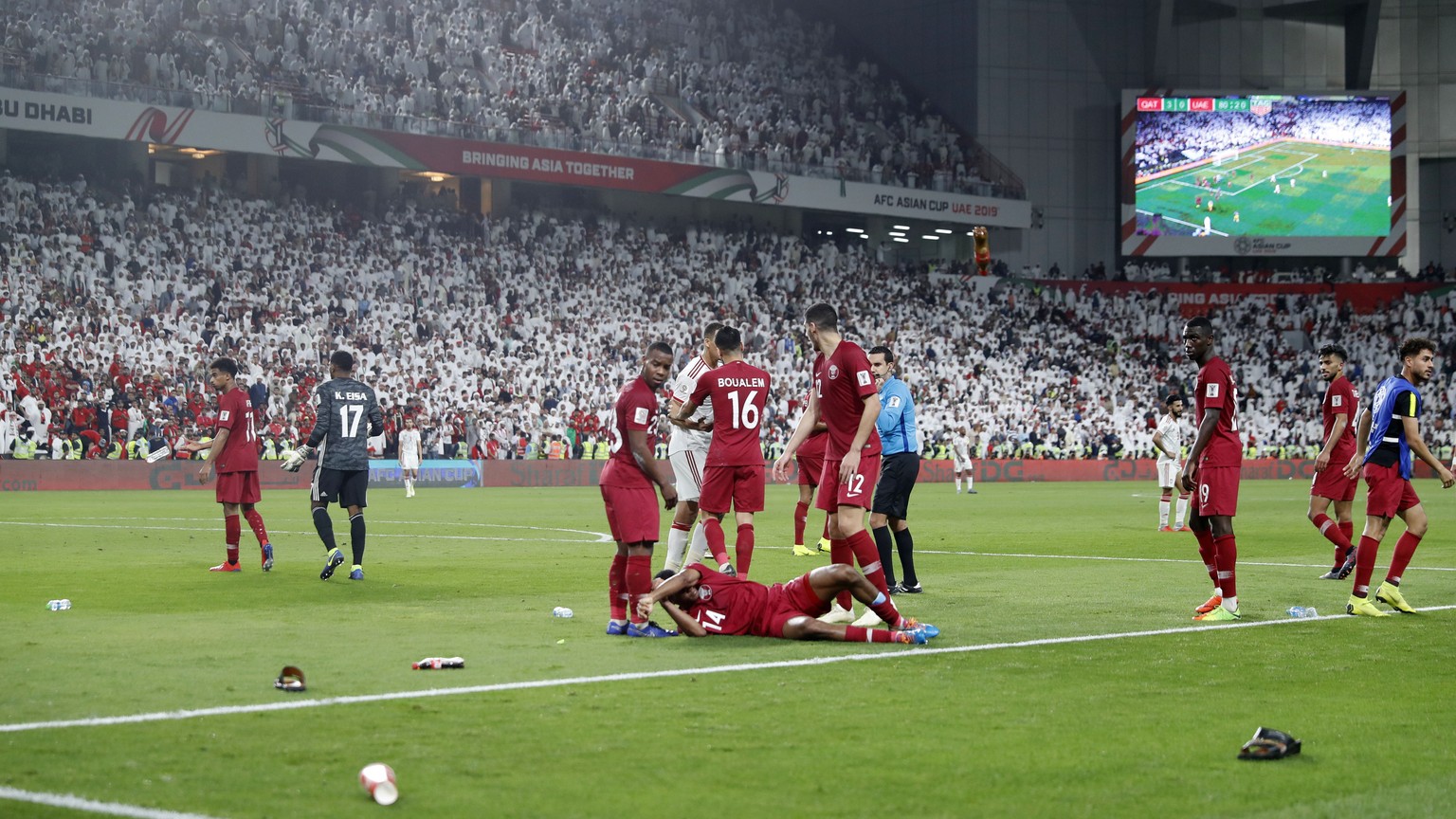 Qatar&#039;s defender Salem Al Hajri, lies on the pitch after shoes and bottles where thrown in by United Arab Emirates fans during the AFC Asian Cup semifinal soccer match between United Arab Emirate ...