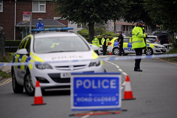 Police officers are seen behind the police cordon in the Keyham area of Plymouth, England, Friday Aug. 13, 2021. Police in southwest England say several people were killed, including the suspected sho ...