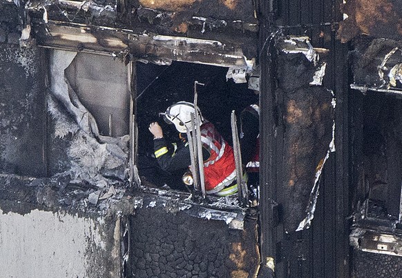 A firefighter checks damage after a fire engulfed the 24-storey Grenfell Tower, in west London, Wednesday June 14, 2017. Fire swept through a high-rise apartment building in west London early Wednesda ...