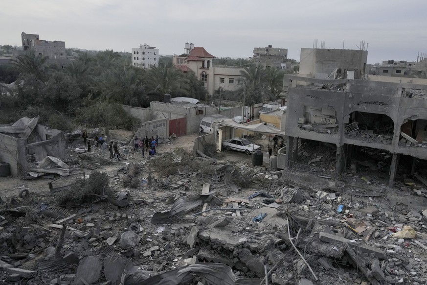 Palestinians look at buildings destroyed in the Israeli bombardment of Al Zawayda, central Gaza Strip, on Sunday, Dec. 10, 2023. (AP Photo/Hatem Moussa)