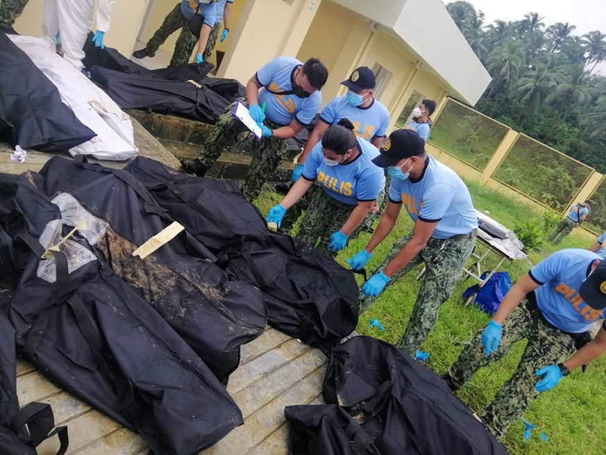 epa09885469 A handout photo made available by the Philippine National Police (PNP) Matalom Police Station shows policemen conduct identification of landslide victims in Baybay city, Leyte province, Ph ...