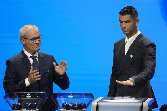 UEFA&#039;s Giorgio Marchetti watches player Cristiano Ronaldo press a button to proceed with the Champions League, league phase, draw, in Monaco, Thursday, Aug. 29, 2024. (AP Photo/Gregorio Borgia)